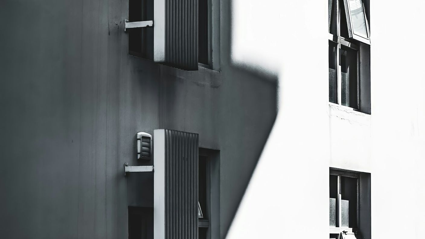 Building facade with an identical grid of windows where only some stand open, contrasting uniform activity with divergent outcomes