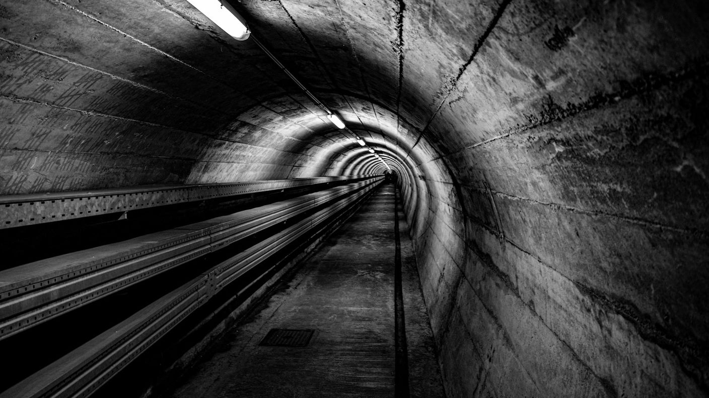 Long dark concrete tunnel with overhead lights and no visible exit, evoking the repeating loop of failed enterprise AI pilots