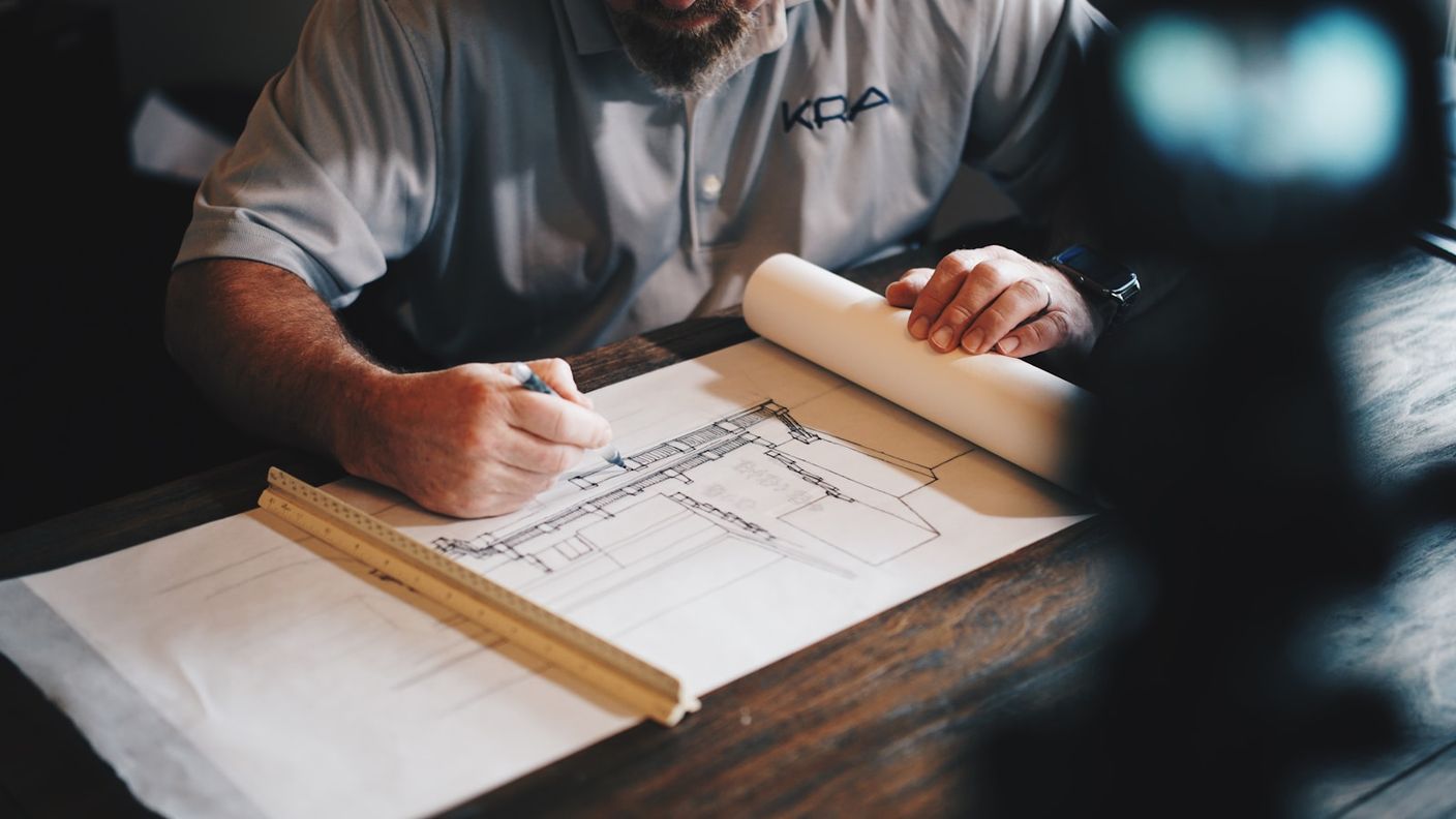 Engineer drawing precise lines on a technical plan with pencil and ruler, reflecting the diligence buyers owe an AI vendor evaluation